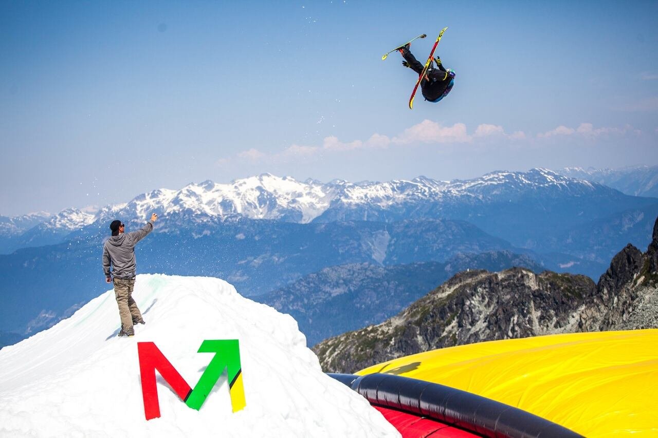 A person is shown watching a moguls skier on a mountain.