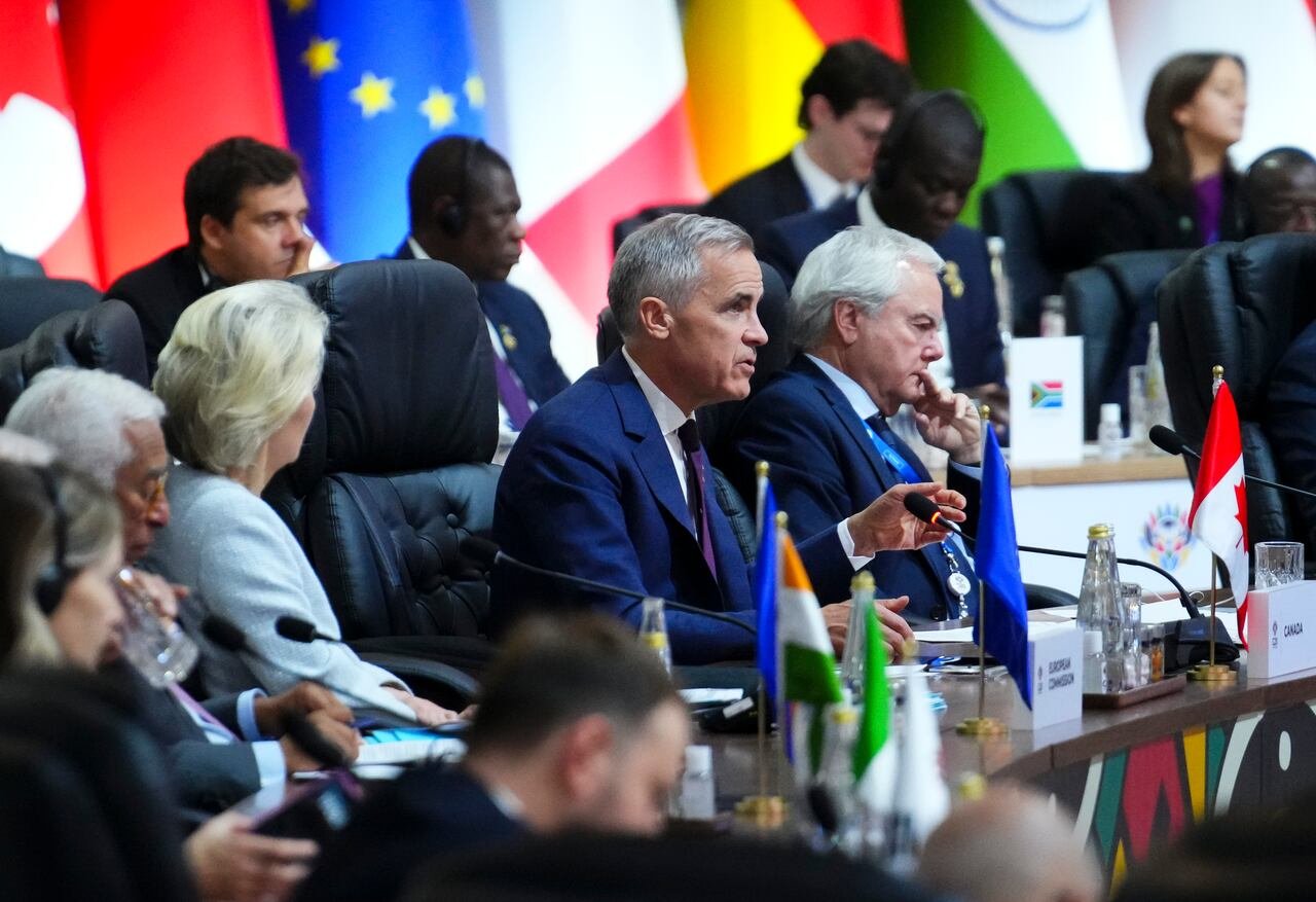 default-546 A man in a suit sits at a table with others in the background.