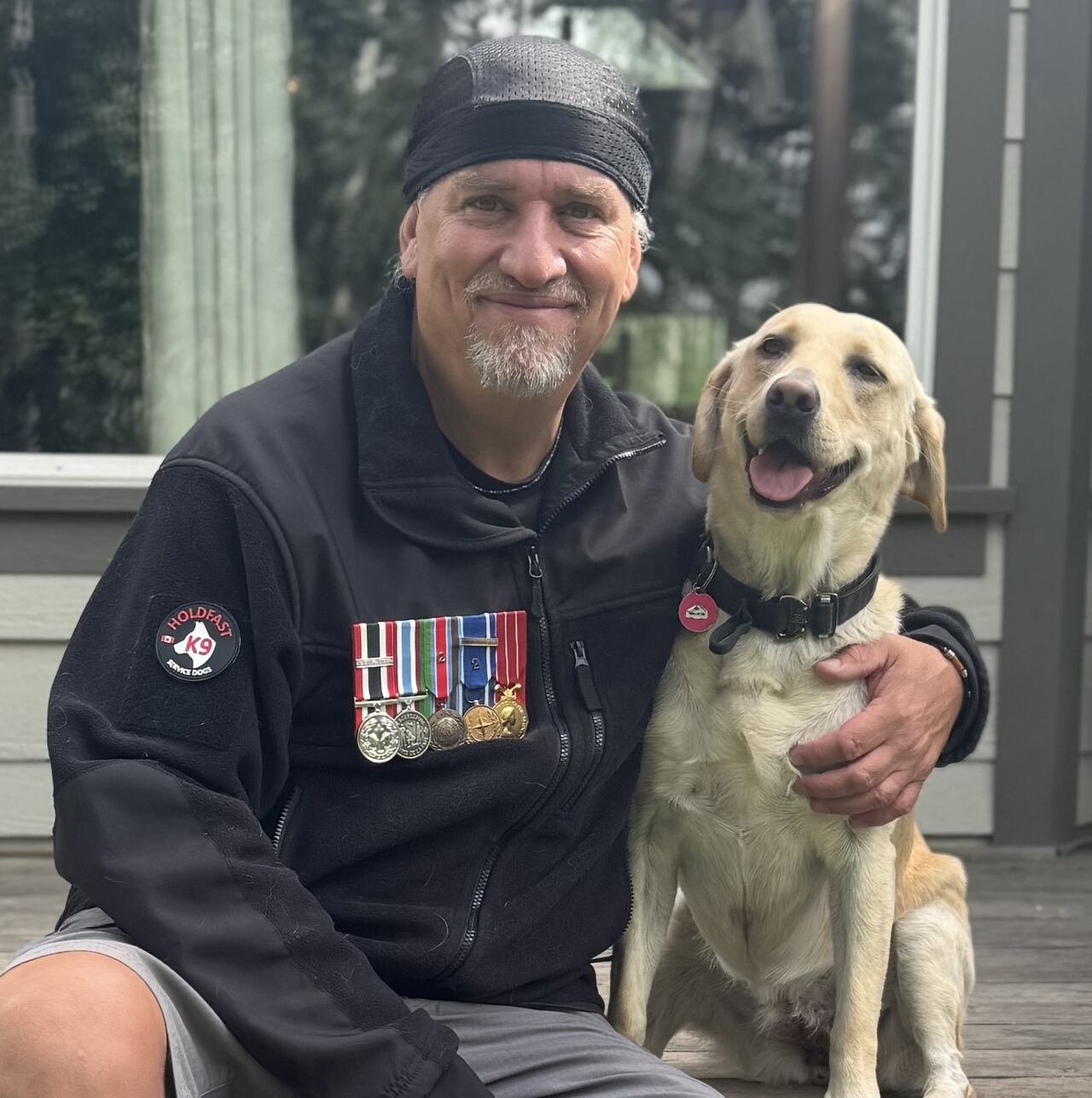 Man with military pins on his jacket, posing with a dog.
