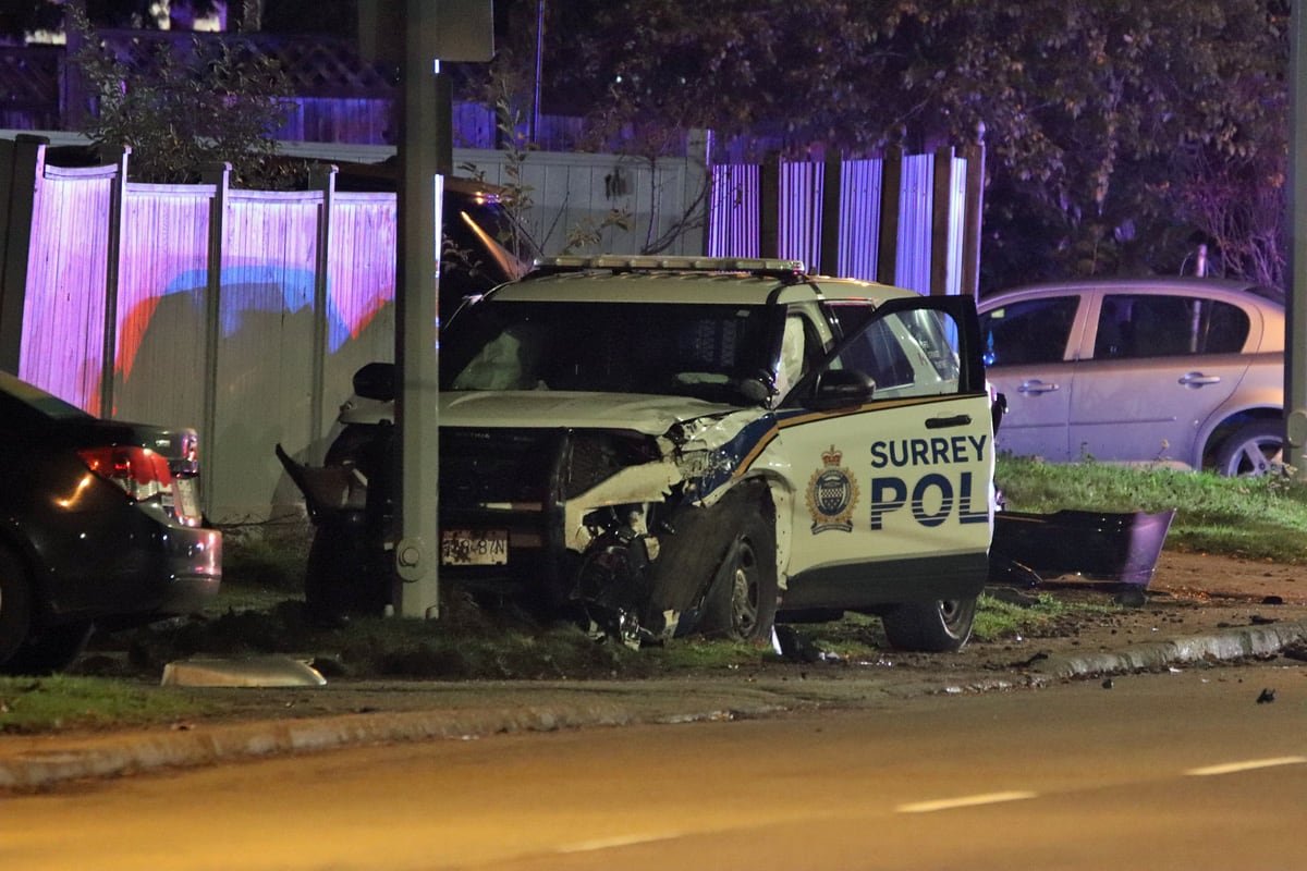 default-606 A marked, white and blue Surrey Police Service SUV photographed at night with its front end crumpled and the passenger side door open.