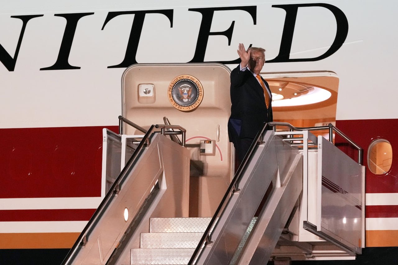 default-120 A man waves from the top of the staircase leading to an airplane.