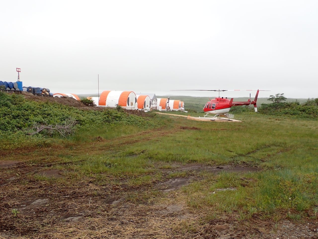 default-827 Multiple tents in an open grass area with a helicopter nearby in a mineral exploration camp North of Burgeo, N.L. in 2023.